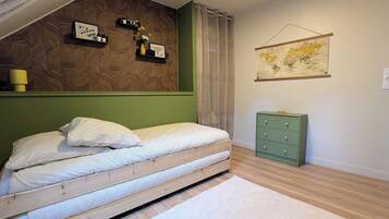 Una habitación con una cama, un aparador verde, un mapa del mundo y estantes con adornos.