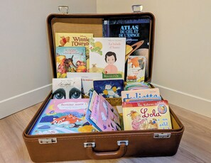 Une valise marron remplie de différents livres pour enfants.