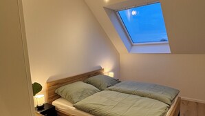 Un dormitorio con tragaluz, estructura de cama de madera y mesitas de noche.