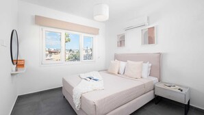 Un dormitorio con cama, mesita de noche, ventana con vistas y aire acondicionado.