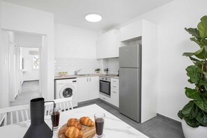 A modern kitchen with a washing machine, oven, and refrigerator. - Nostalgia Residence by Nomads (Paphos)