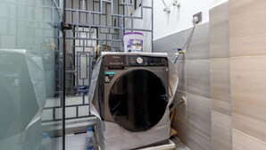 Una lavanderia funzionale con lavatrice a carica frontale, cancello metallico e scaldabagno.
