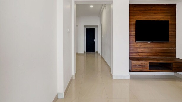 A hallway with a wooden entertainment unit and a flat-screen TV mounted on it. - Premiumcoastal Inn 3 (Kakinada)