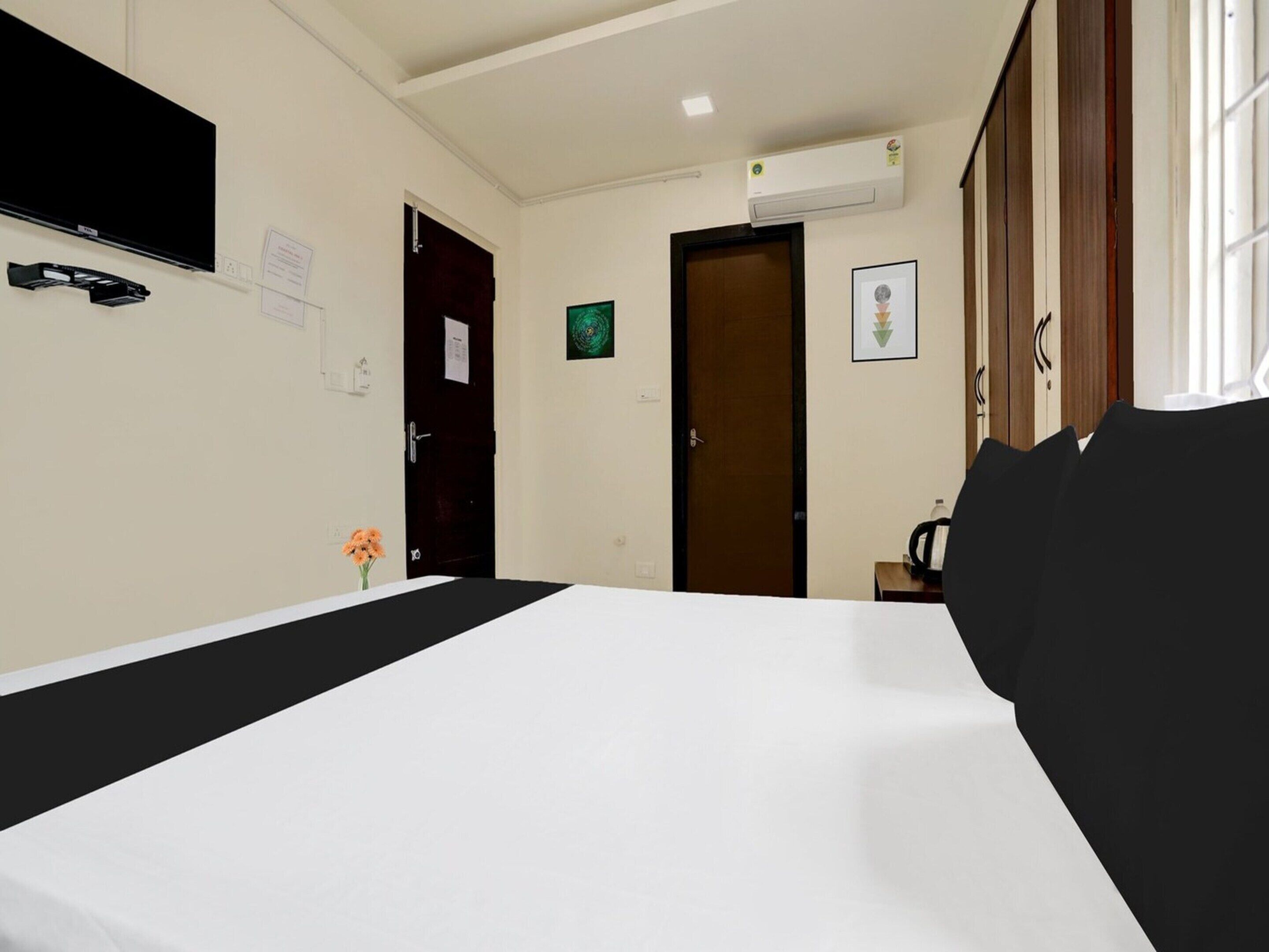 Quarto de hotel com uma cama, televisão de tela plana, uma mesa pequena com uma garrafa de água e um quadro na parede.