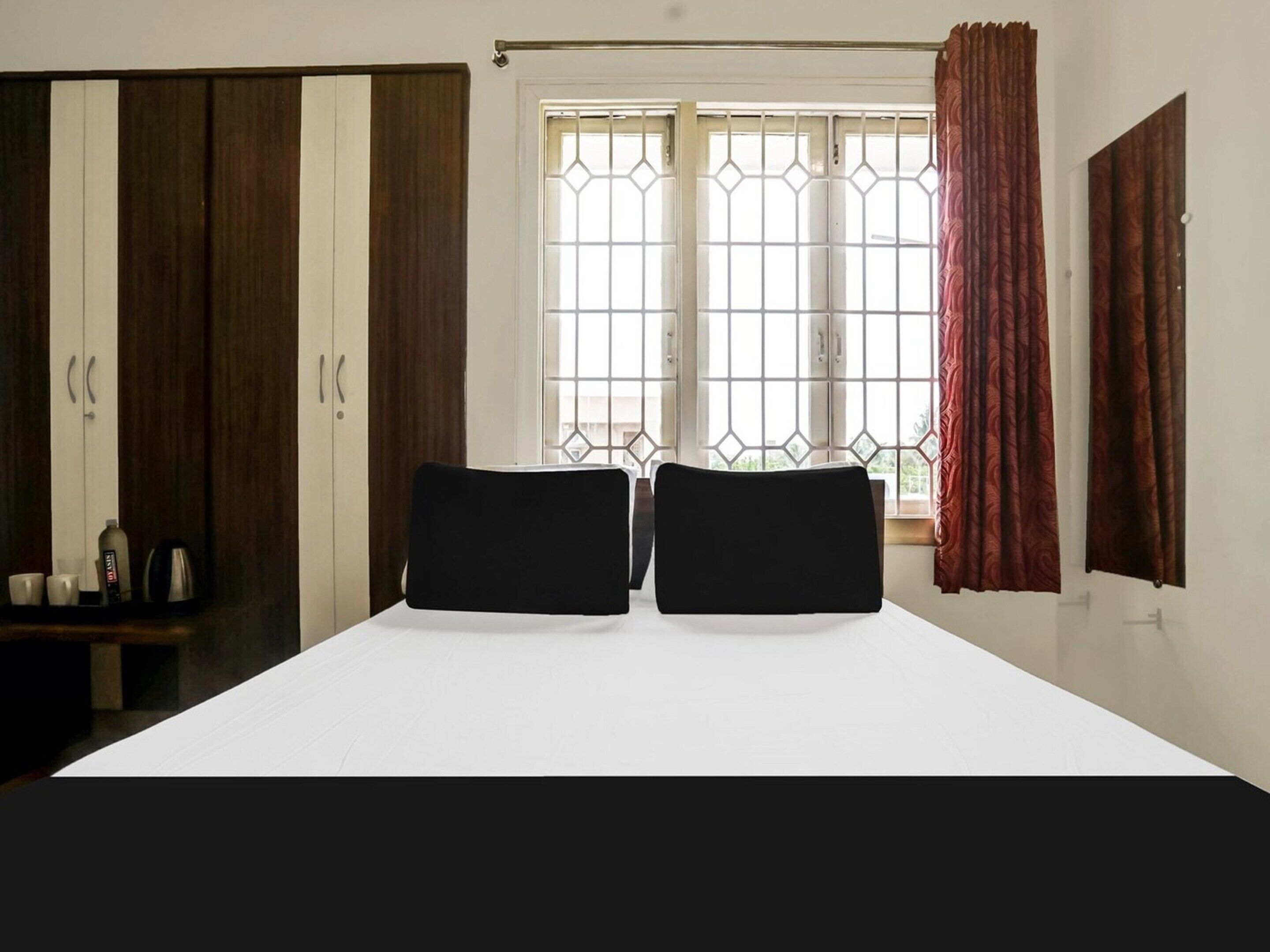 A bedroom with a bed, two black headboards, a window with metal bars, and a wardrobe.