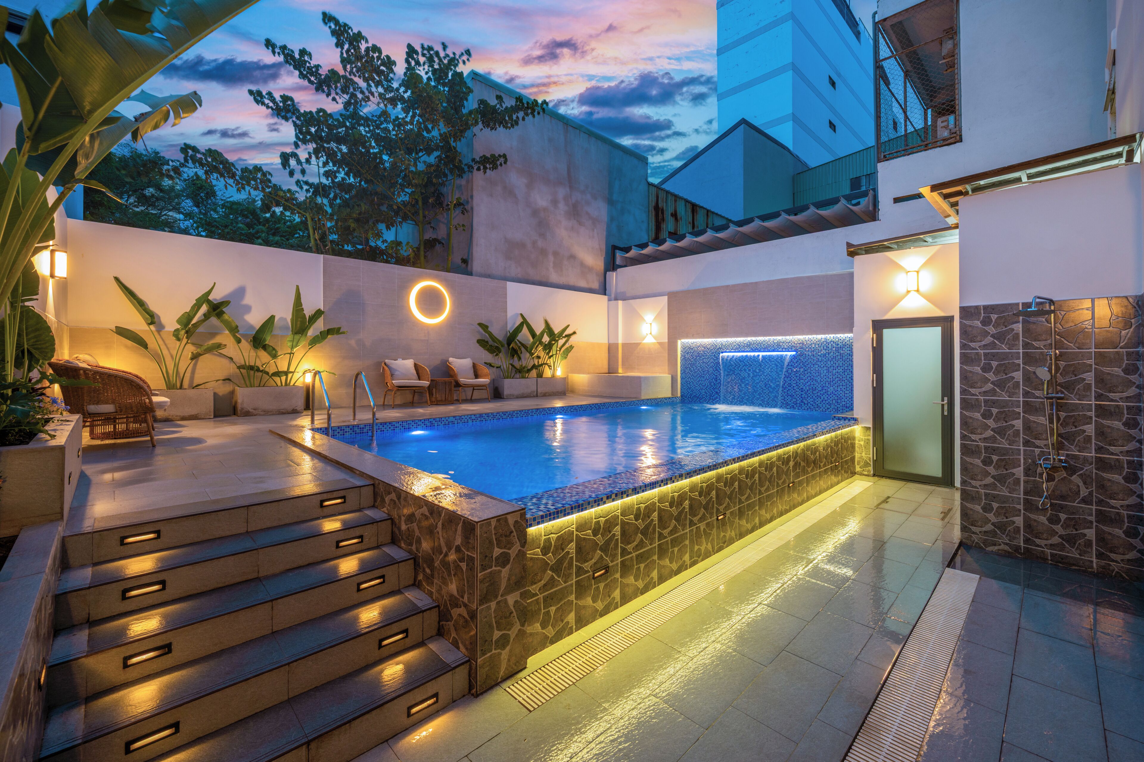 A swimming pool with steps leading up to it, surrounded by lounge chairs and potted plants.