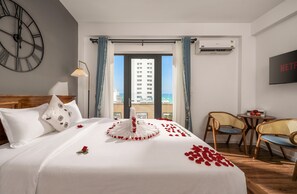 Ein Hotelzimmer mit einem Bett, einer Uhr, einem Fernseher und Blick auf Gebäude.