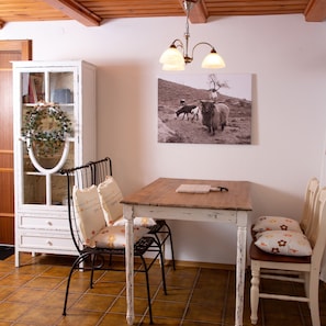 A dining area with a wooden table, two chairs, a cabinet, and a wall-mounted picture. - Cottage 'Lieblingsplatz Am Bach' with Wi-Fi (Windorf)
