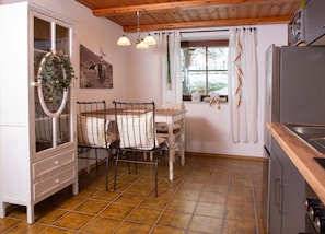 A compact kitchen with a dining area, a refrigerator, and a window with curtains. - Cottage 'Lieblingsplatz Am Bach' with Wi-Fi (Windorf)