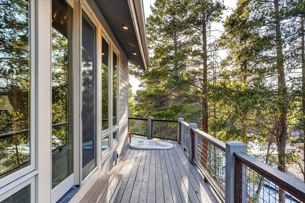 A wooden deck with a hot tub, large windows, and a view of trees. - Mountain Retreat • Hot Tub | Near Keystone Resort | Keystone Alpine Haven (Keystone)