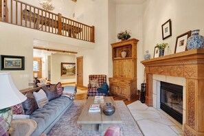 A spacious living room with a high ceiling, a fireplace, a wooden cabinet, and a sofa. - Mountain Retreat • Hot Tub | Near Keystone Resort | Keystone Alpine Haven (Keystone)