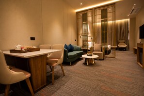 Een hotelkamer met een eethoek, een bank, een salontafel en een televisie.