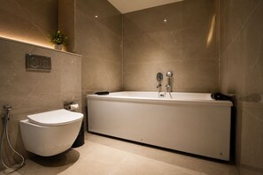 Een moderne badkamer met toilet, ligbad en douche.