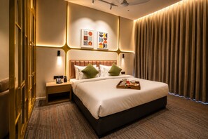 Een hotelkamer met een groot bed, een nachtkastje met een telefoon, en een dienblad met ontbijtartikelen.