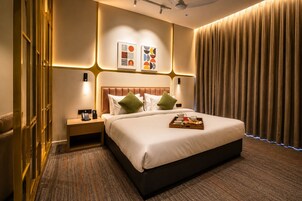 Habitación de hotel con una cama grande, una mesita de noche con teléfono y una bandeja con alimentos para el desayuno.