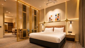A hotel room with a large bed, a desk, and a chair, a wardrobe, and a bathroom. - West Adorn by The Sky Imperial, Ahmedabad (Sanand)