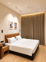 Una habitación de hotel moderna con una cama grande, una mesita de noche con teléfono y un ventilador de techo.