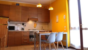 Une cuisine avec des meubles de rangement en bois, un four à micro-ondes, une cuisinière et une table à manger avec des chaises.