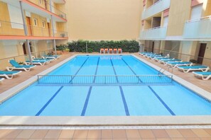 Una piscina amb gandules i un edifici amb balcons.