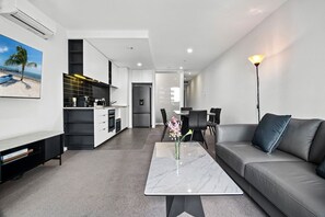 Un salon moderne comprenant un canapé, une table basse et un coin repas avec des chaises.