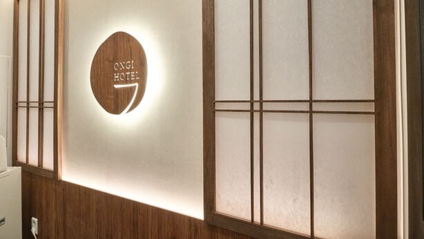 A wall with a circular sign that reads 'ONGI HOTEL' and a wooden panel with a grid pattern. - Hongdae Ongi Hotel (Seoul)