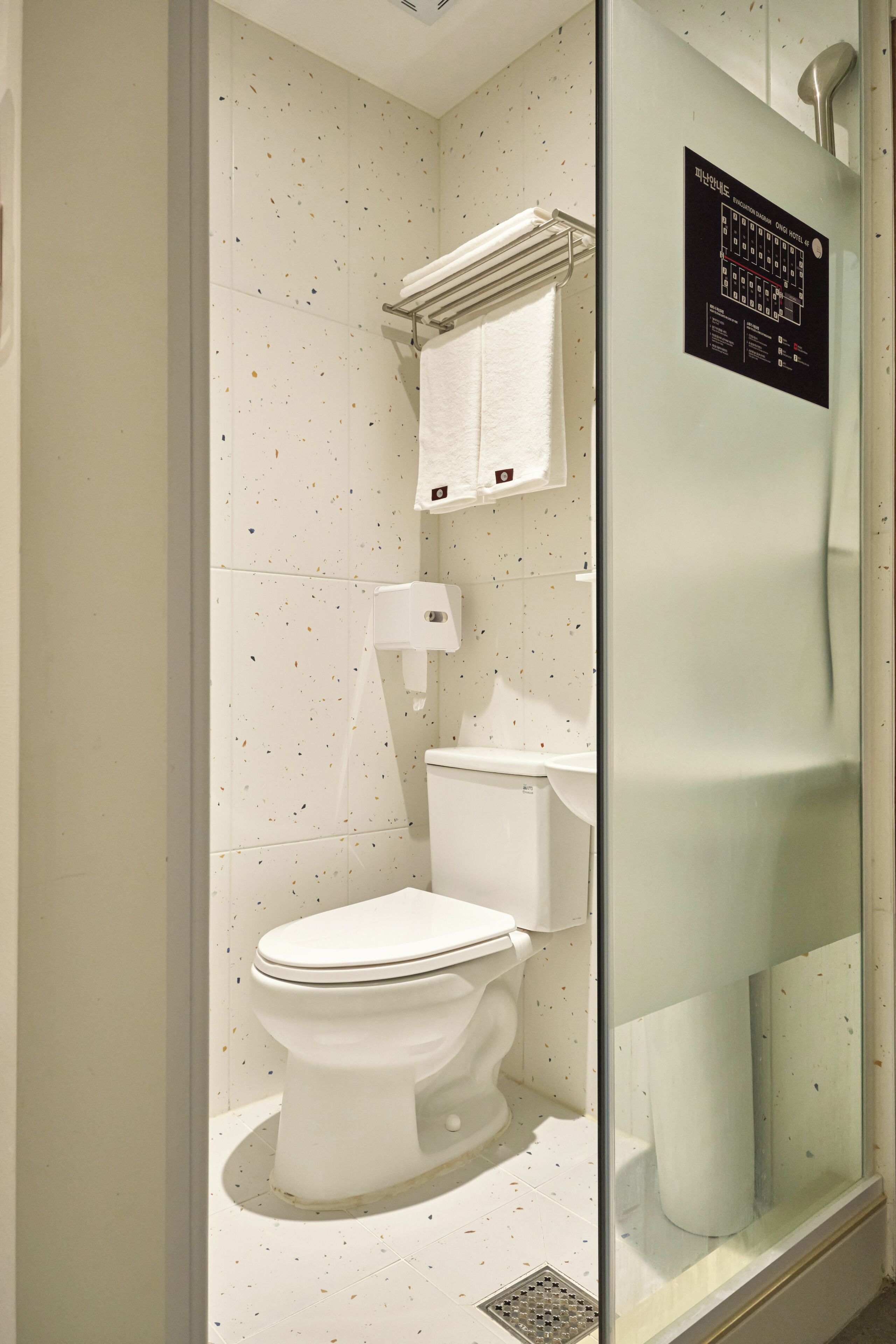 Un bany modern amb un vàter blanc, un espai de dutxa amb envàs de vidre i un lavabo blanc.