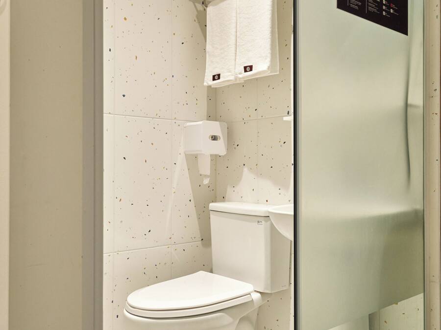 Un bany modern amb un vàter blanc, un espai de dutxa amb envàs de vidre i un lavabo blanc.