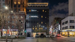 A modern hotel with a prominent sign, a crosswalk, and surrounding urban buildings. - Hongdae Ongi Hotel (Seoul)