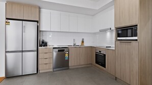 Cuina moderna amb armaris blancs, electrodomèstics d'acer inoxidable i un rentaplats.