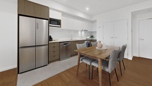 Eine moderne Küche mit Edelstahlgeräten, einem Holztisch und grau gepolsterten Stühlen.
