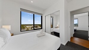 Camera d'albergo moderna con un letto grande, vista sulla città e uno specchio che riflette l'ambiente.