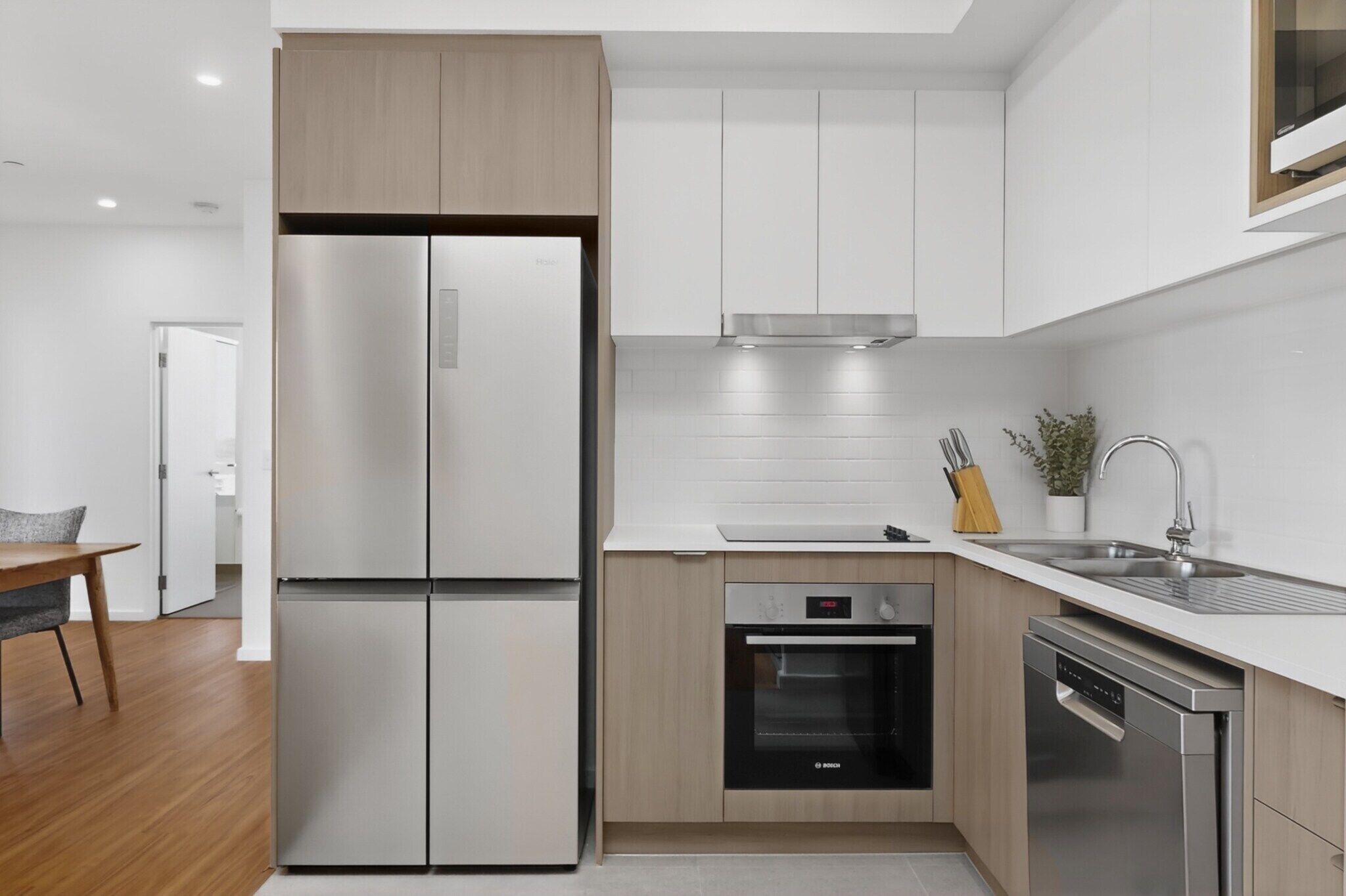 A modern kitchen with a stainless steel refrigerator, oven, dishwasher, and a sink with a faucet.