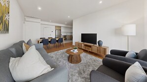 En moderne stue med sofa, sofabord og fjernsyn.