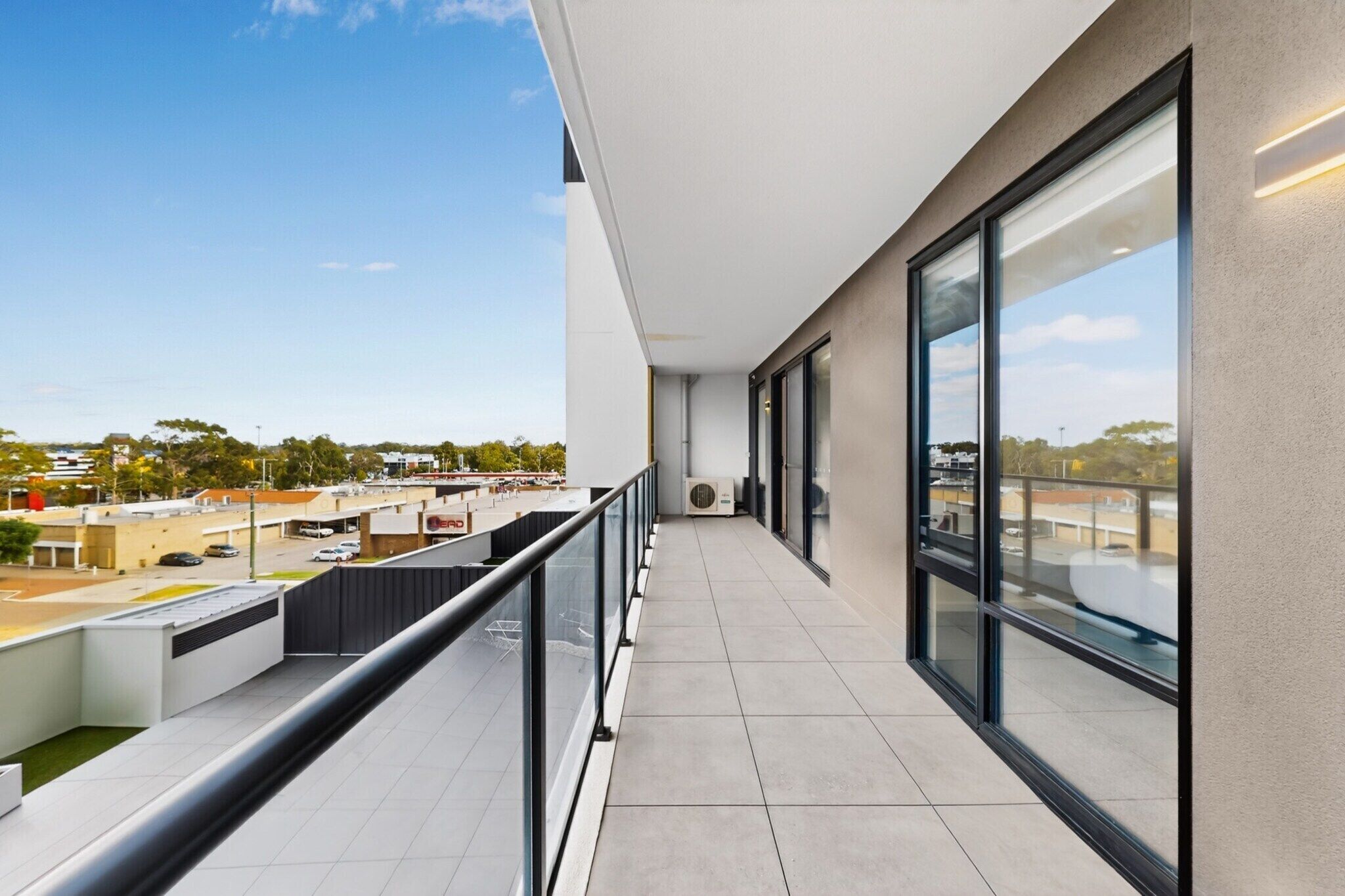 Un balcon moderne donnant sur un parking et des immeubles.