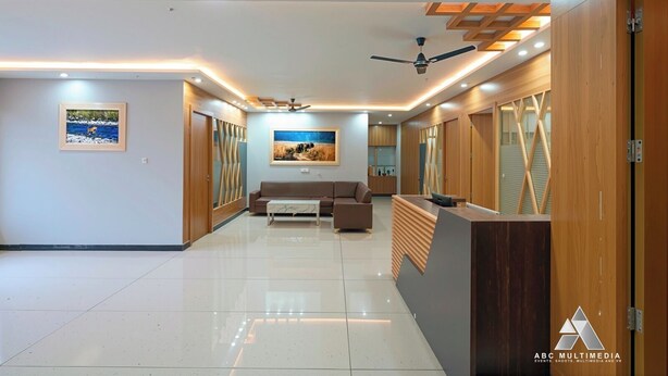 A spacious hallway with a reception desk, a ceiling fan, recessed lighting, and a large painting on the wall. - Countrywide Corbett (Ramnagar)