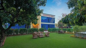 A modern building with a sign reading 'COUNTRYWIDE GROUP' and a well-maintained lawn with outdoor furniture. - Countrywide Corbett (Ramnagar)
