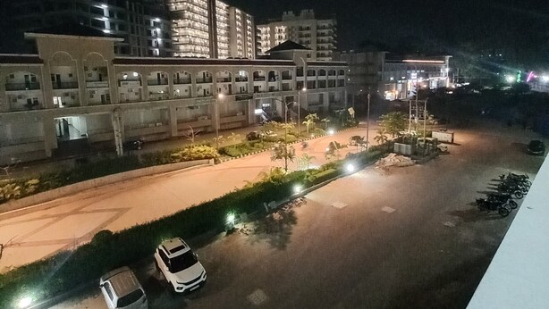 Vista nocturna de un estacionamiento con varios automóviles y un edificio al fondo.