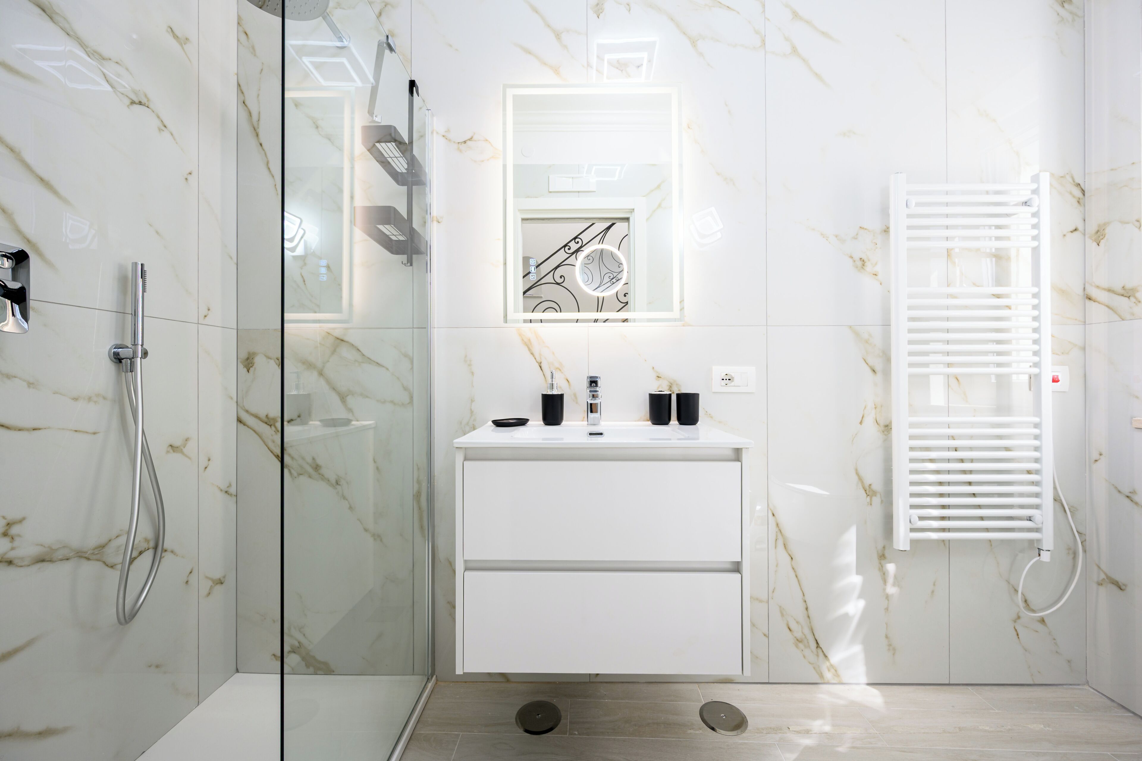 A modern bathroom with a glass shower enclosure, a white vanity with a mirror, and a built-in towel rack.