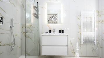A modern bathroom with a glass shower enclosure, a white vanity with a mirror, and a built-in towel rack.