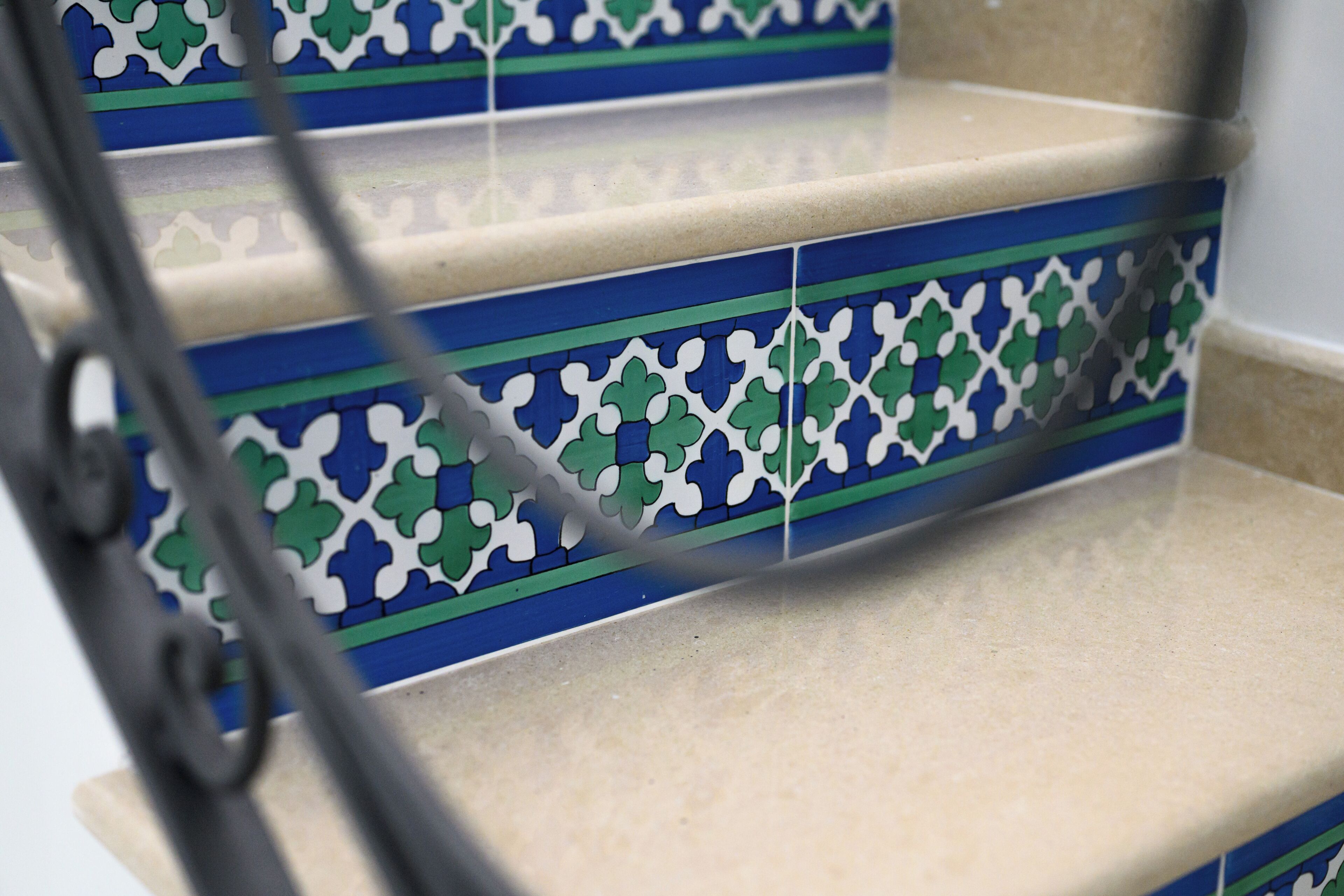 Un escalier orné de carreaux décoratifs et doté d’une rampe en métal.