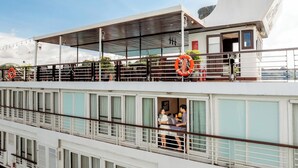 A multi-deck cruise ship with outdoor seating areas, lifebuoys, and a covered deck. - Lan Ha Bay 4 Star Cruise  (Tuan Chau)