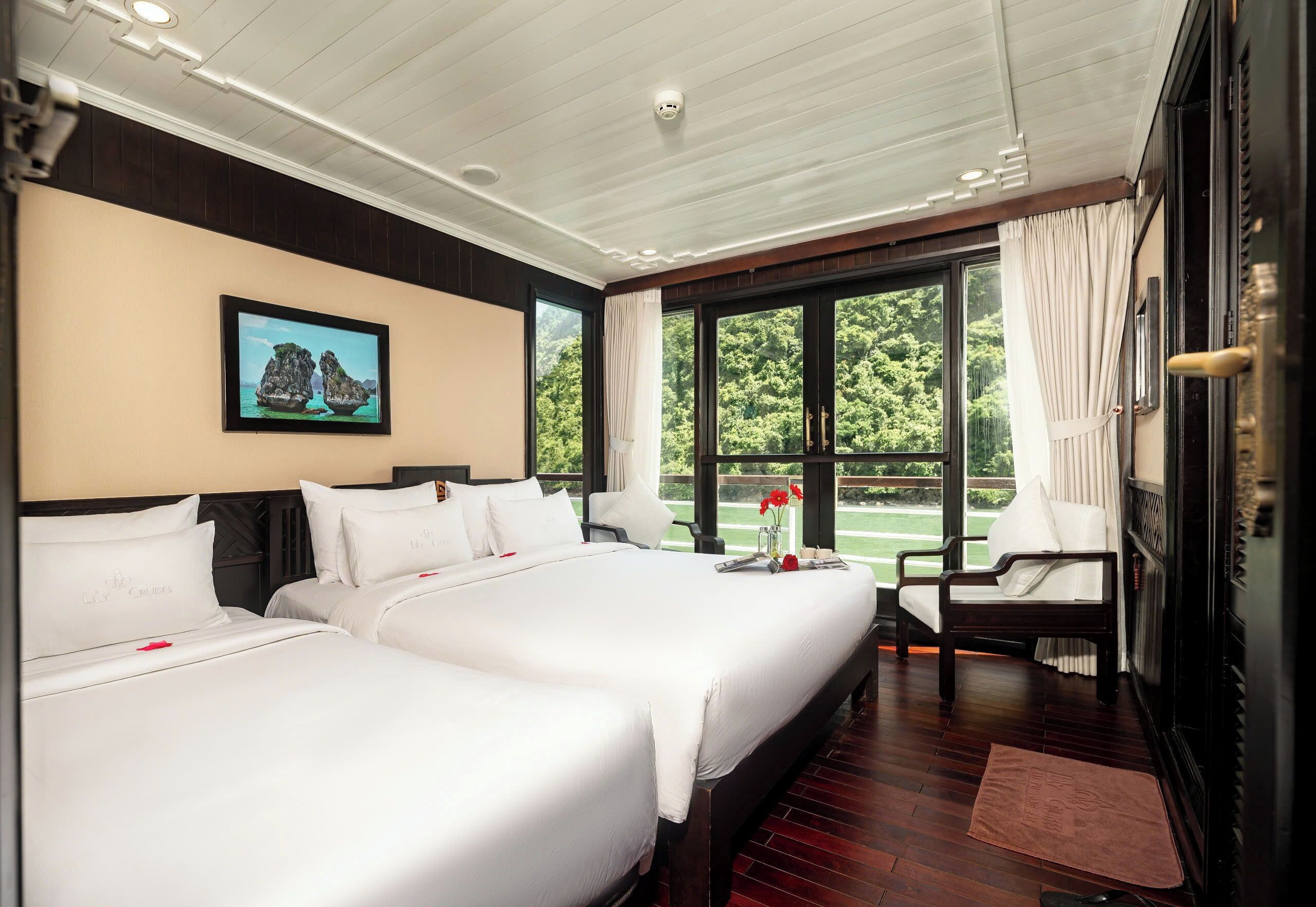 A hotel room with two beds, a large window with curtains, a chair, and a painting on the wall.