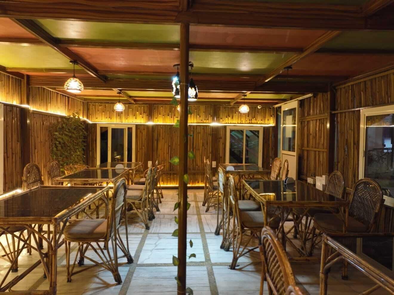 Un comedor con paredes de madera, mesas de vidrio y sillas de mimbre.