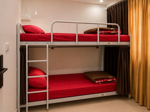 A bunk bed with red bedding, a white metal frame, a wall-mounted lamp, and a curtain. - V4Y Hotel 4U Tapovan Rishikesh (Rishikesh)
