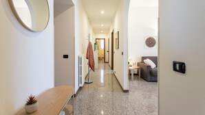 A hallway with a round mirror, a small plant, a radiator, a sofa, and a table with a lamp. - Apartment in Como with 2 bedrooms sleeps 6 (Como)