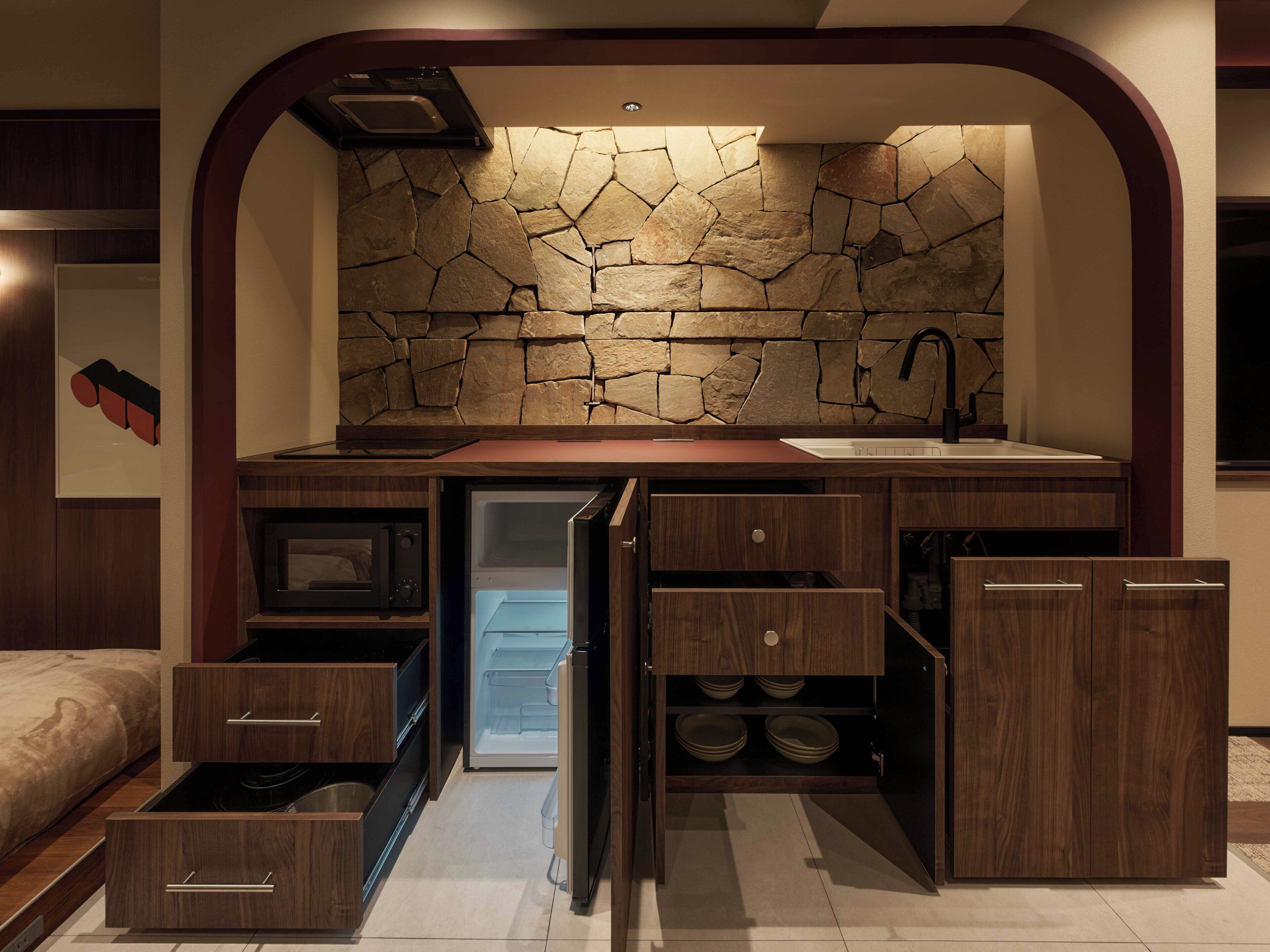 A compact kitchen with a stone backsplash, built-in appliances, and wooden cabinetry.