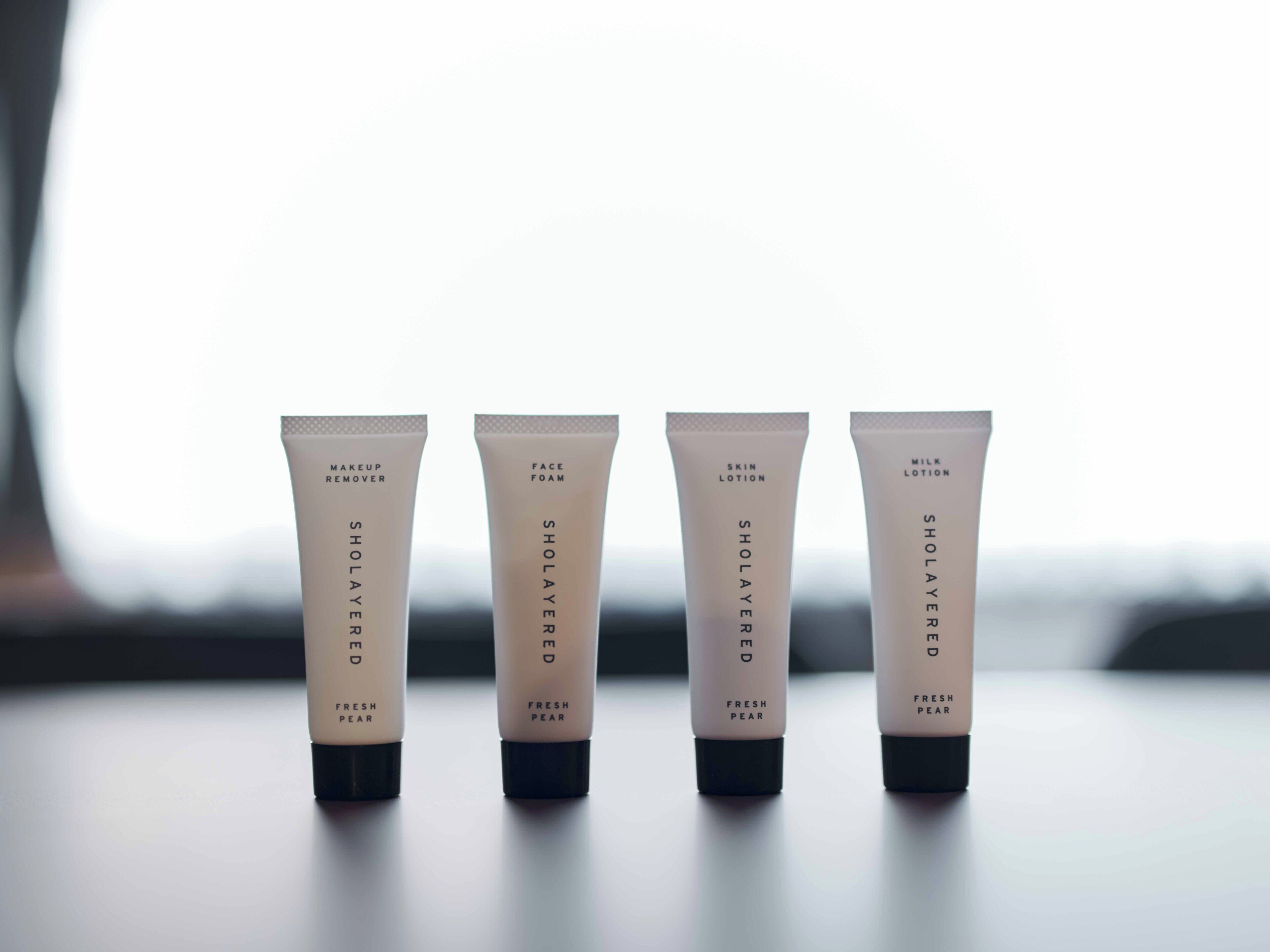 Four skincare product tubes labeled 'SHOLAYERED FRESH PEAR' on a table.