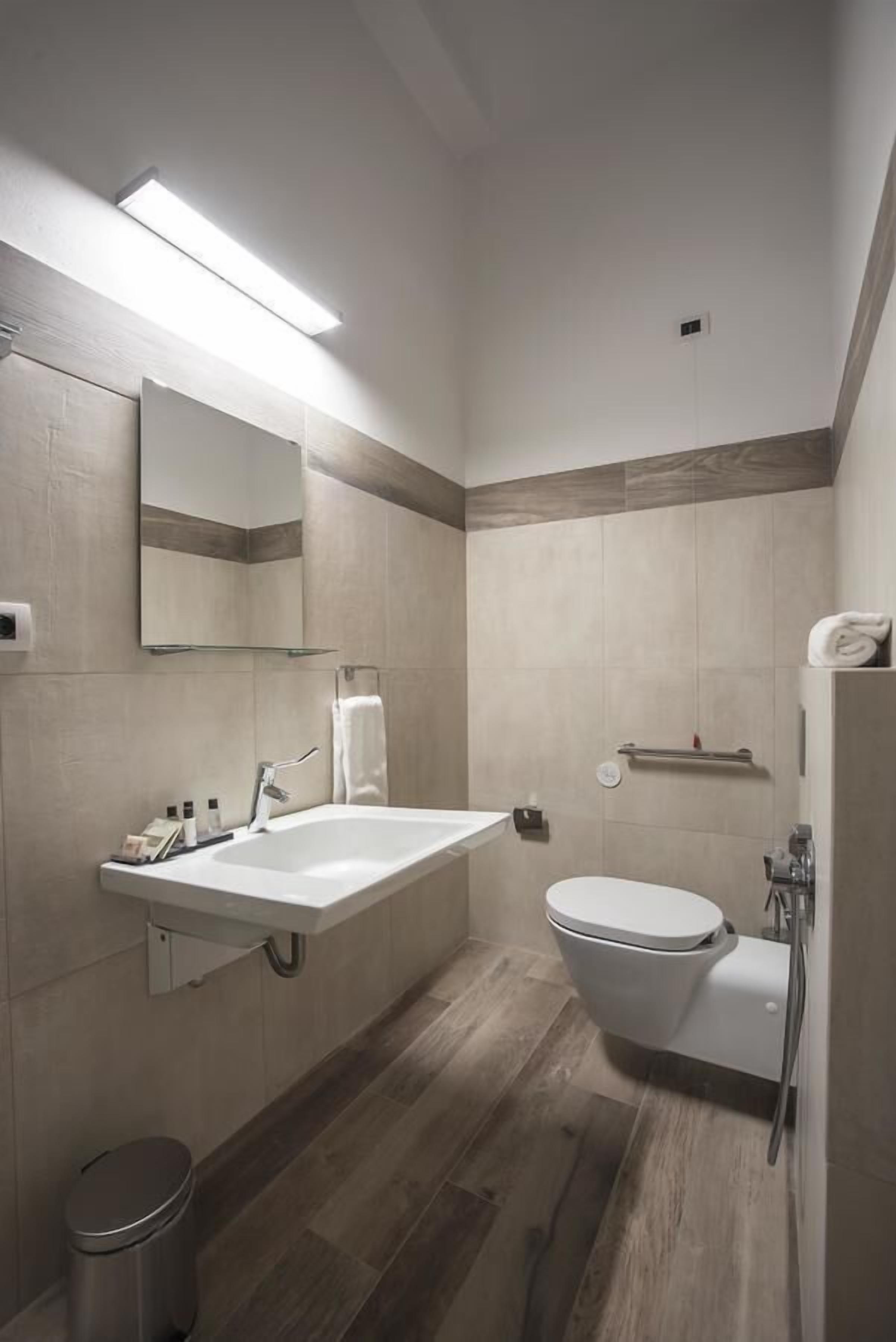 A modern bathroom with a large sink, mirror, toilet, and shower.