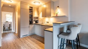 A modern kitchen with white cabinets, a bar area, and a dining space with chairs. - Princessa Coast - Holiday home "Princessa Coast" (Sylt)