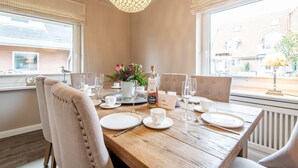 A dining table set for four with a bottle of liquor, glasses, and a vase of flowers. - Princessa Coast - Holiday home "Princessa Coast" (Sylt)
